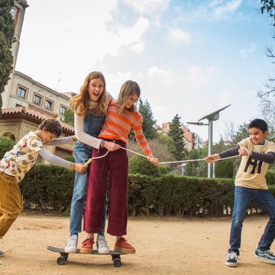 4 Kinder, die mit einem Skateboard und dem Springseil von Me&Mine spielen.